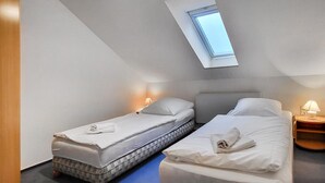 A small, modern bedroom with two beds, a skylight, and bedside lamps. - Nice apartment in Goslar with WiFi (Goslar)