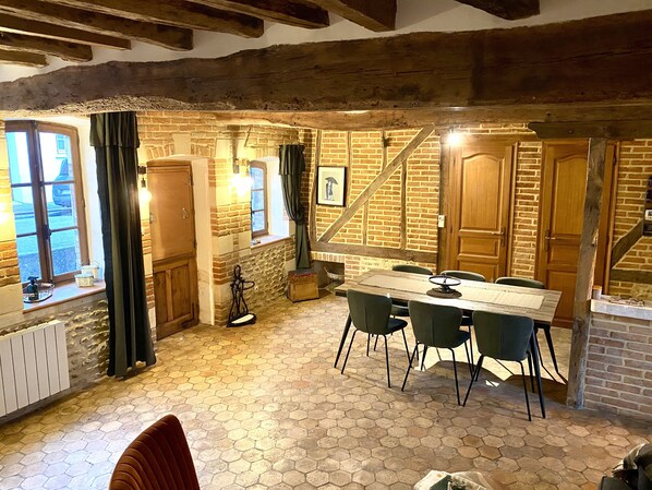 Enjoy meals in this charming dining area with a long table for four, brick wall, and exposed beams.