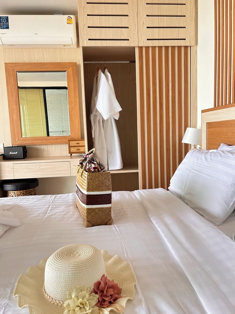 A hotel room with a bed, a wardrobe, a mirror, and a bedside table.