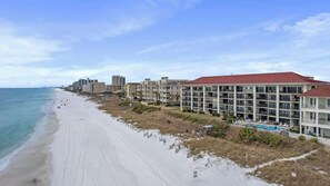 Un hôtel en bord de mer, avec plusieurs étages, une piscine et vue sur la plage.