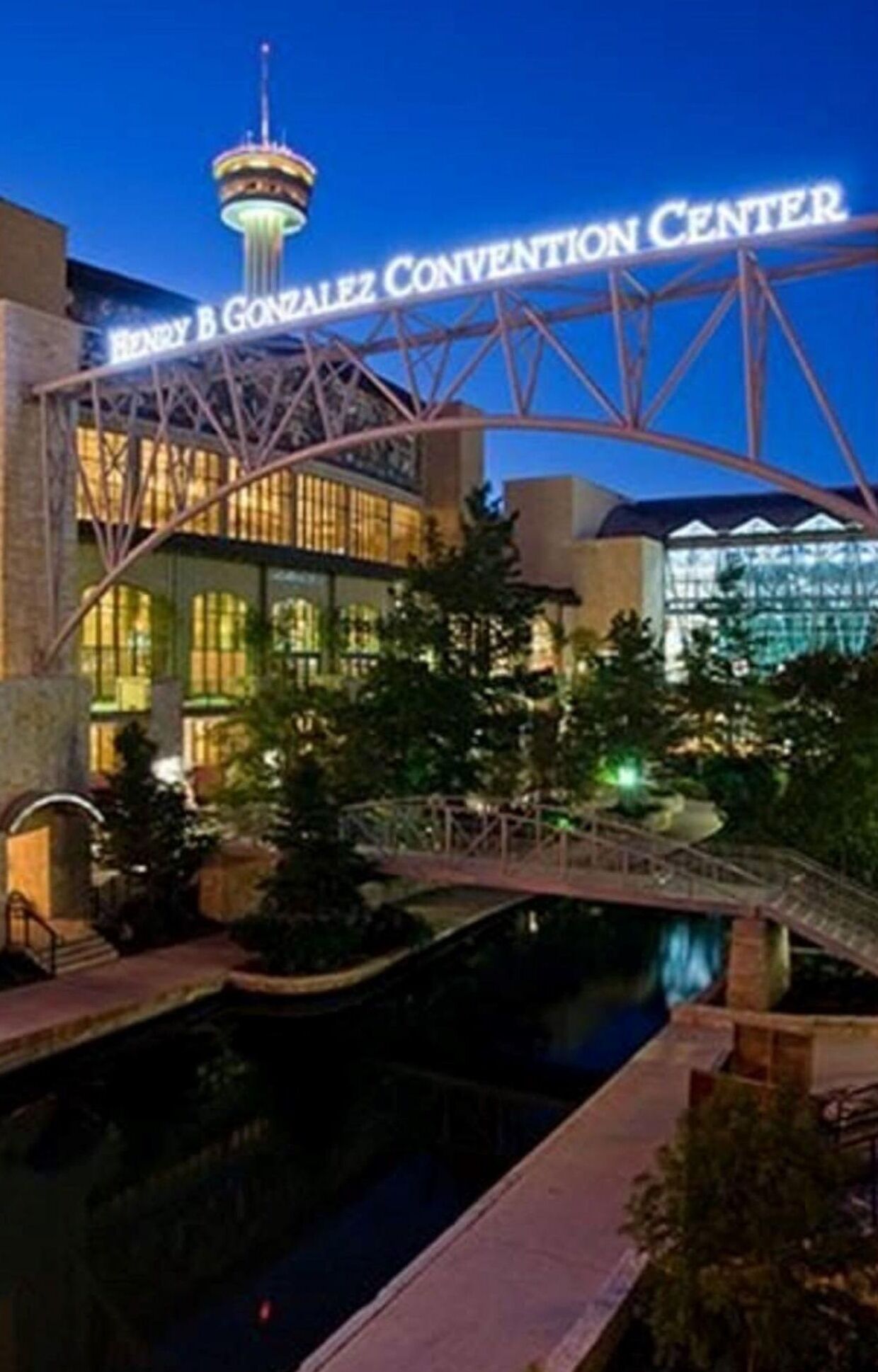 Exterior del Centro de Convenciones Henry B. Gonzalez con un puente sobre un elemento acuático.