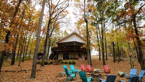 Une cabane entourée d’arbres, avec un espace extérieur aménagé pour s’asseoir.
