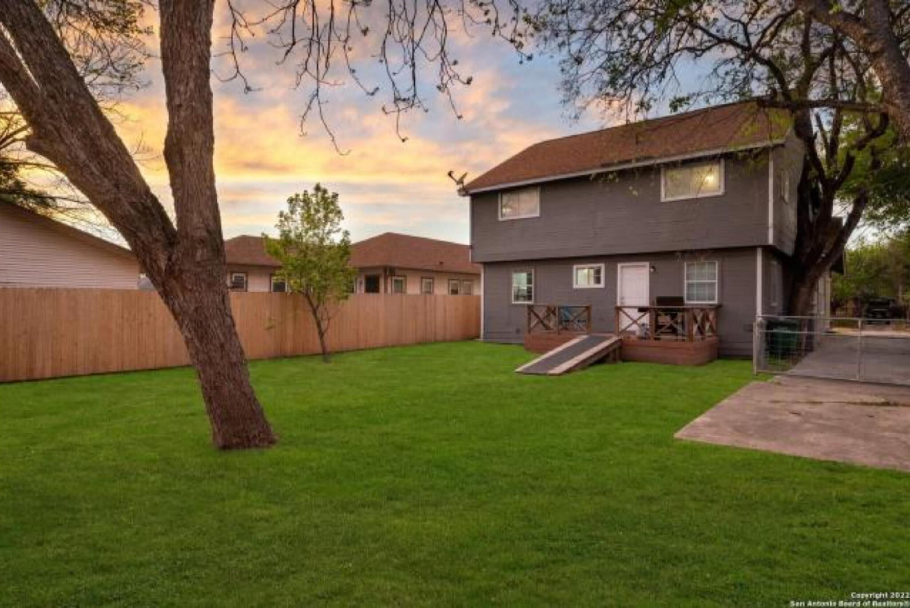 A two-story house with a well-maintained lawn and a wooden deck.
