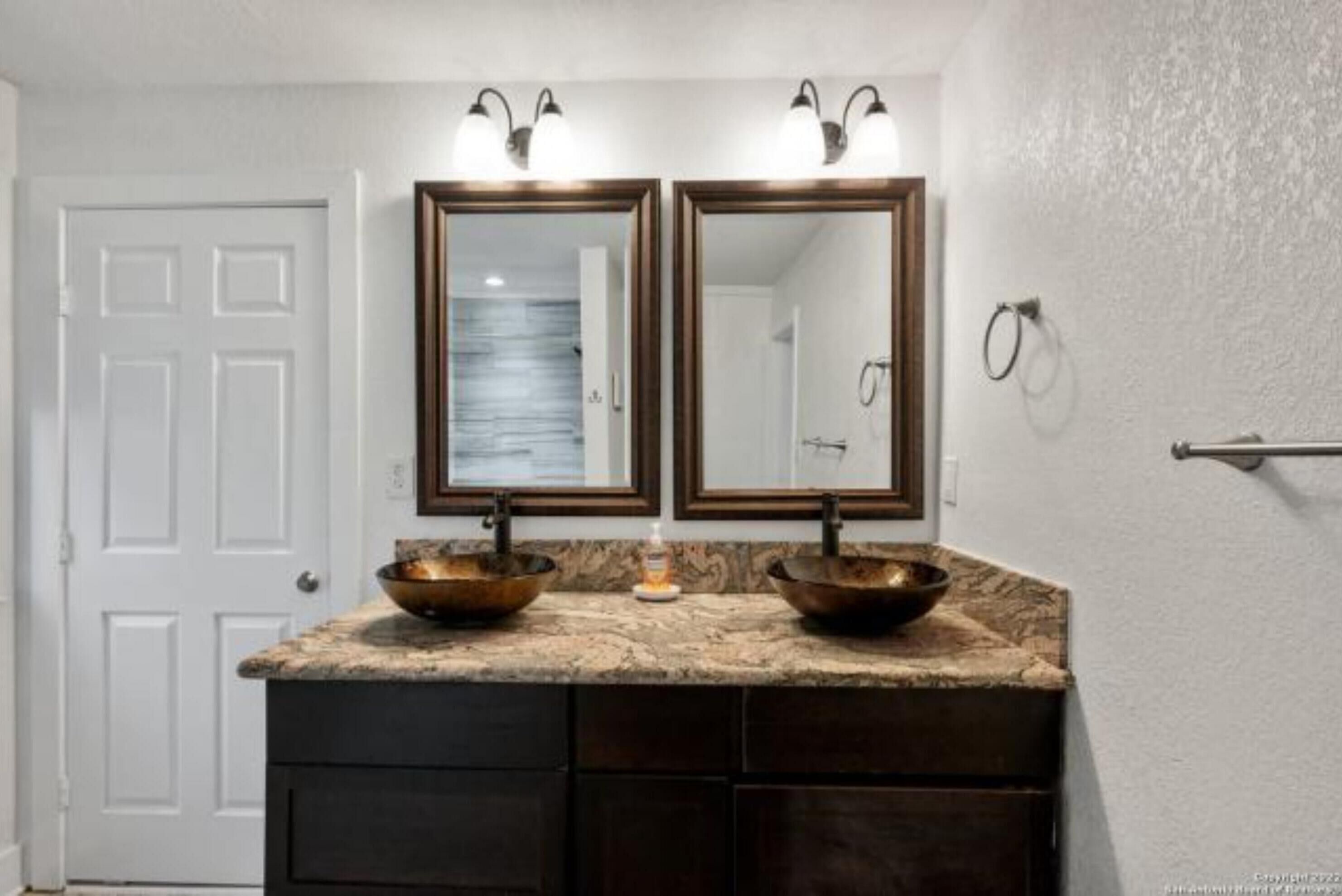 A bathroom with a double sink vanity, two wall-mounted mirrors, and a towel rack.