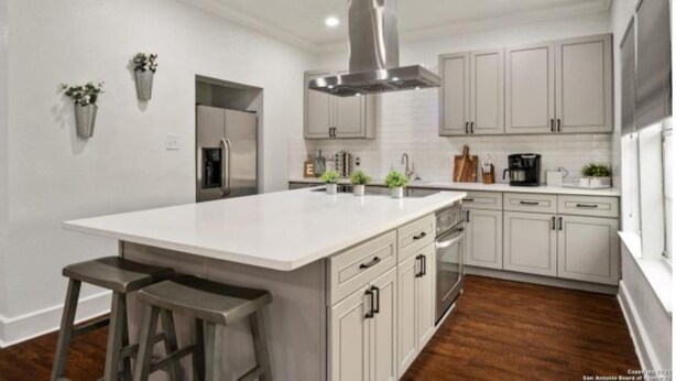 A modern kitchen with a large island, stainless steel appliances, and light-colored cabinetry. - Experience Serenity in a 4BR 3BA Downtown Home (San Antonio)