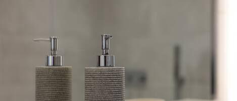 Two cylindrical dispensers on a bathroom counter with a mirror in the background.