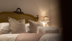 Cama bem arrumada com almofadas, cabeceira, luminária de cabeceira e um enfeite na parede.