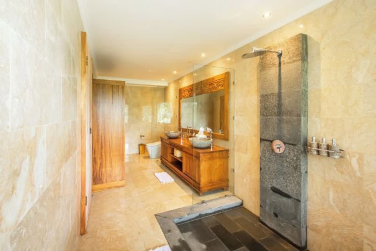 Un baño moderno con cabina de ducha de vidrio, tocador de madera y un espejo grande.