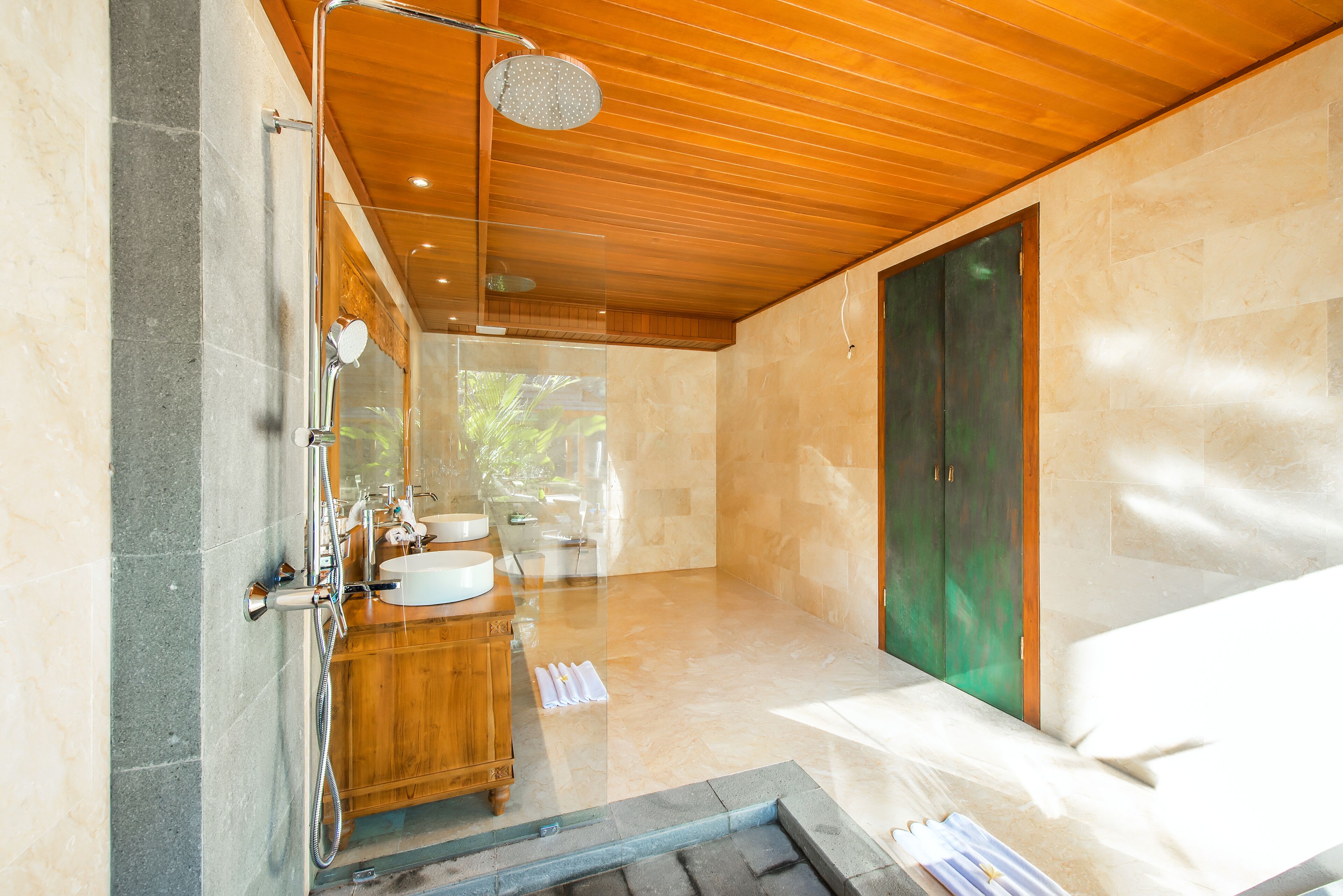 A modern bathroom with a wooden ceiling, a large mirror, a sink, and a shower area.