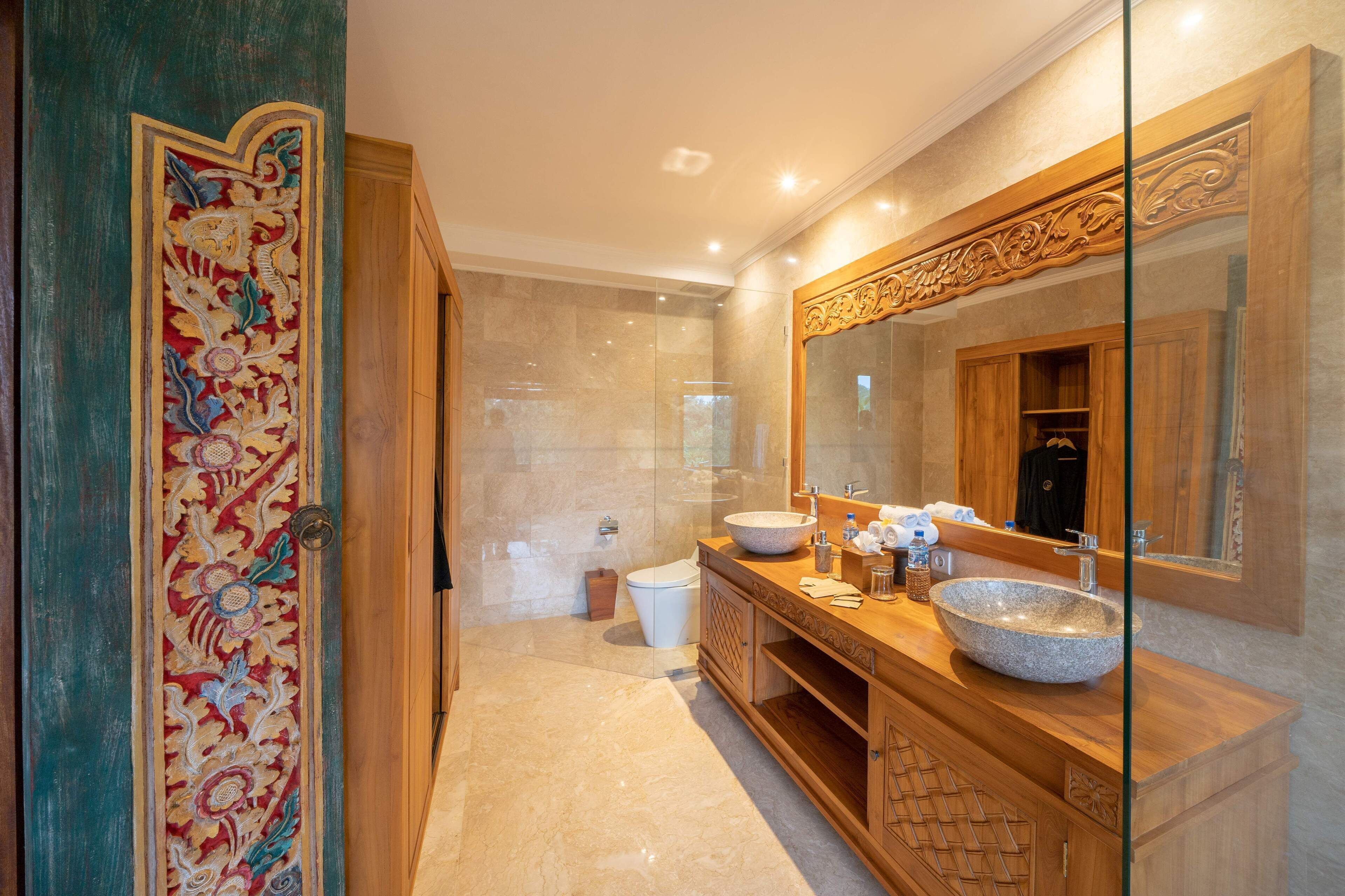 Un baño con tocador de madera, un espejo grande y una puerta decorativa.