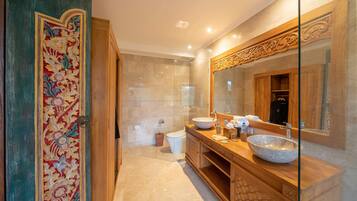 Un baño con tocador de madera, un espejo grande y una puerta decorativa.