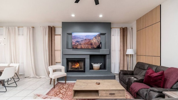A modern living room with a fireplace, a flat-screen TV mounted above it, and a leather sofa. - NEW! Luxury, Scottsdale Getaway! (Scottsdale)