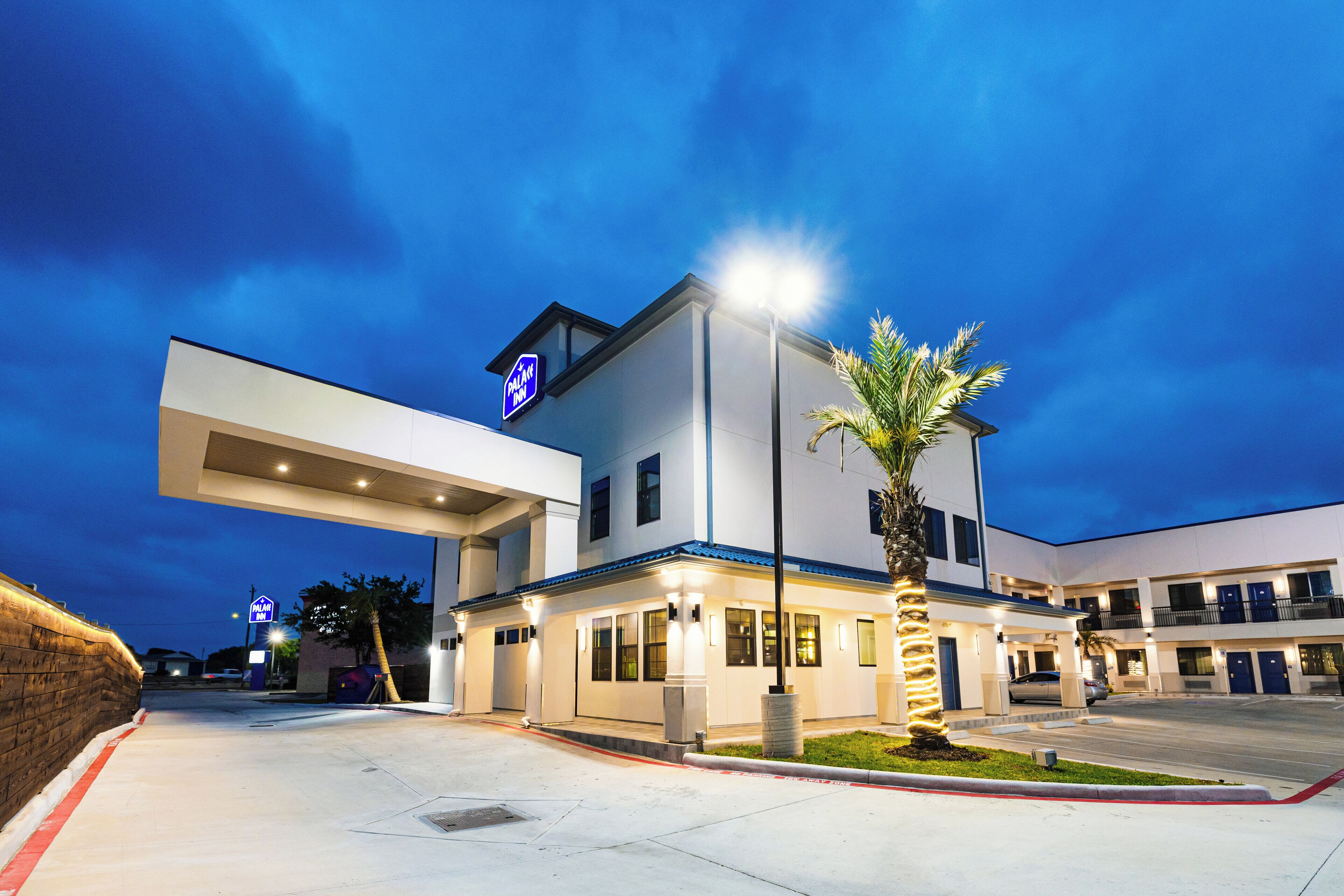 Un hotel moderno con tejado plano, un letrero de estación de servicio y una entrada bien iluminada.