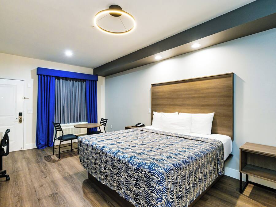Une chambre d’hôtel avec un grand lit, un bureau, une chaise, une petite table et une table de chevet.