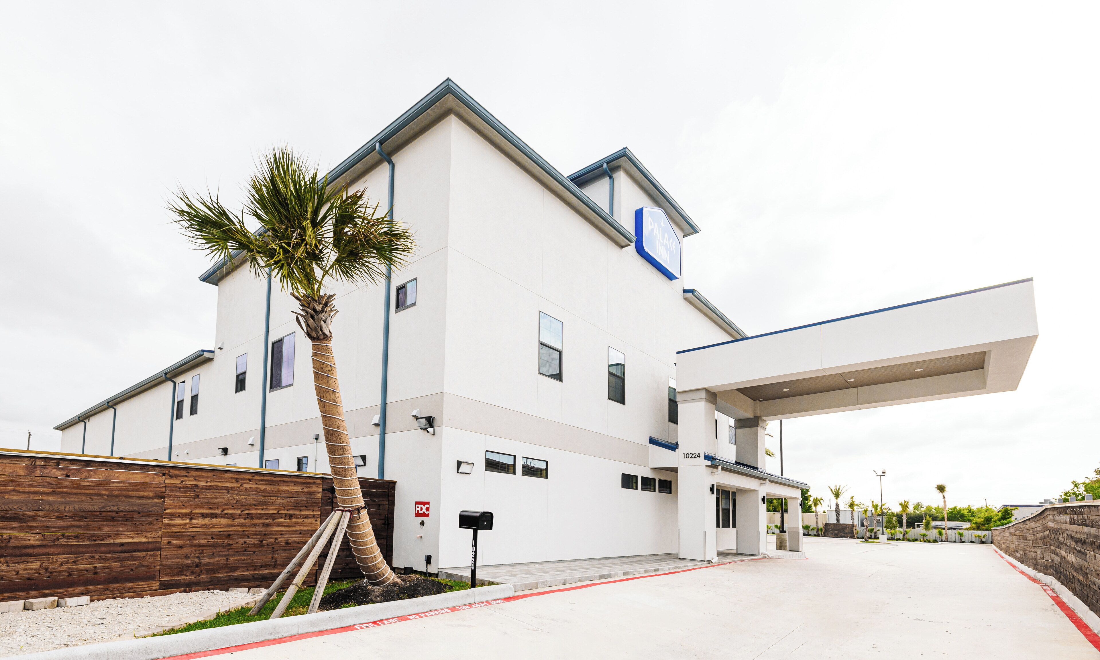 A modern building with a white facade, multiple windows, and a covered entrance.