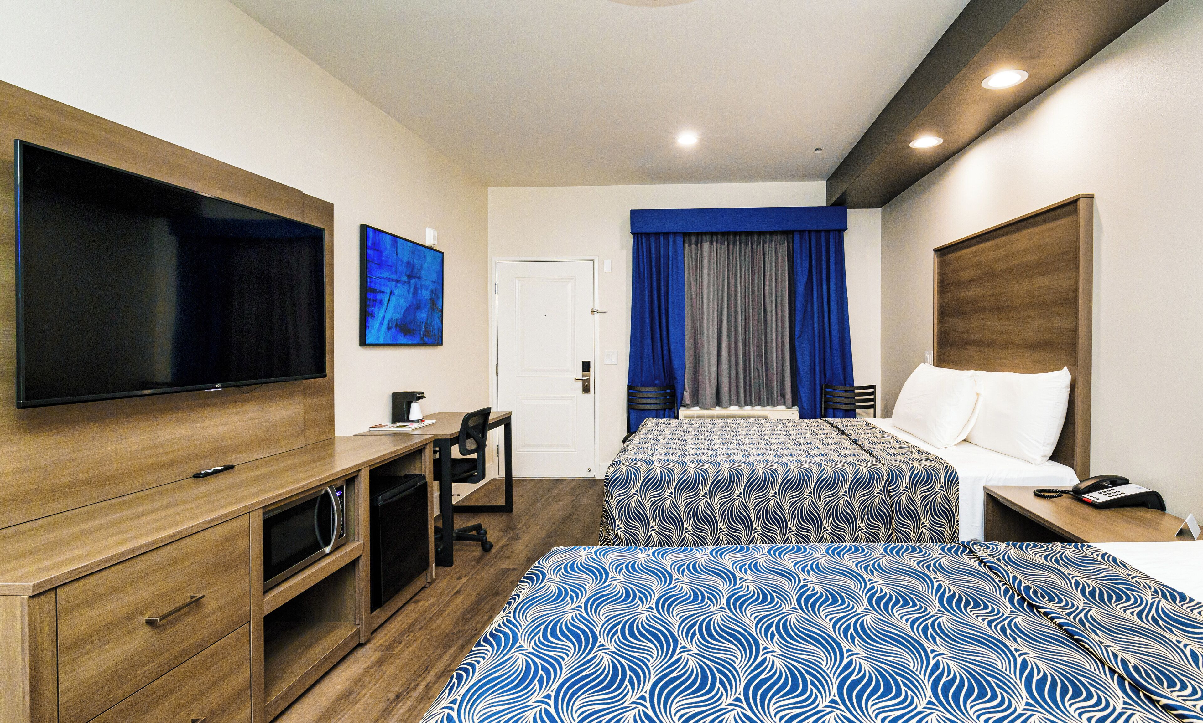 Une chambre d’hôtel avec deux lits, un bureau, une télévision et une porte.