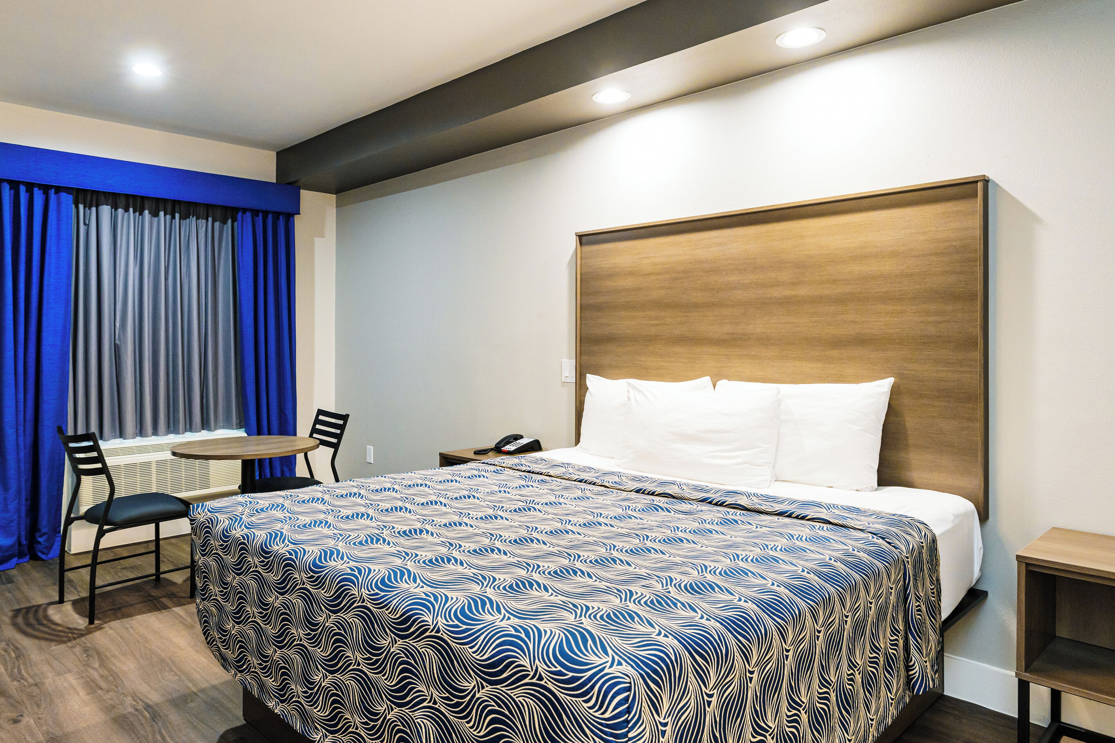 Ein Hotelzimmer mit einem großen Bett, einem kleinen Tisch, zwei Stühlen und einem Schreibtisch.