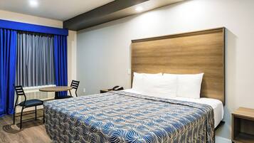 Ein Hotelzimmer mit einem großen Bett, einem kleinen Tisch, zwei Stühlen und einem Schreibtisch.