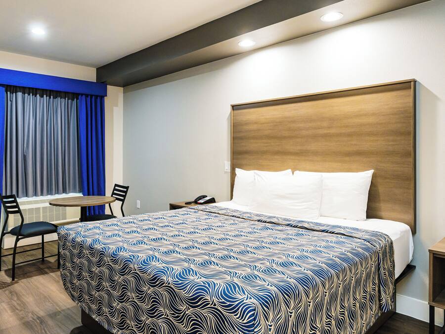 Ein Hotelzimmer mit einem großen Bett, einem kleinen Tisch, zwei Stühlen und einem Schreibtisch.