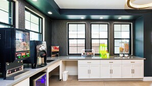 A modern kitchen with a coffee machine, a sink, and a window with a view of a brick wall. -  Palace Inn Blue Edgebrook (Houston)