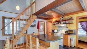A wooden interior with a kitchen area, a wooden staircase, and a dining area with wooden chairs. - Snoqualmie Pass Cabin w/ Deck: Walk to Ski Lift (Snoqualmie Pass)
