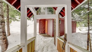 A snow-covered wooden pathway leading to a red building with a white roof. - Snoqualmie Pass Cabin w/ Deck: Walk to Ski Lift (Snoqualmie Pass)