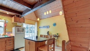 A kitchen with wooden cabinets, a refrigerator, a wooden island, and a dining area with chairs. - Snoqualmie Pass Cabin w/ Deck: Walk to Ski Lift (Snoqualmie Pass)