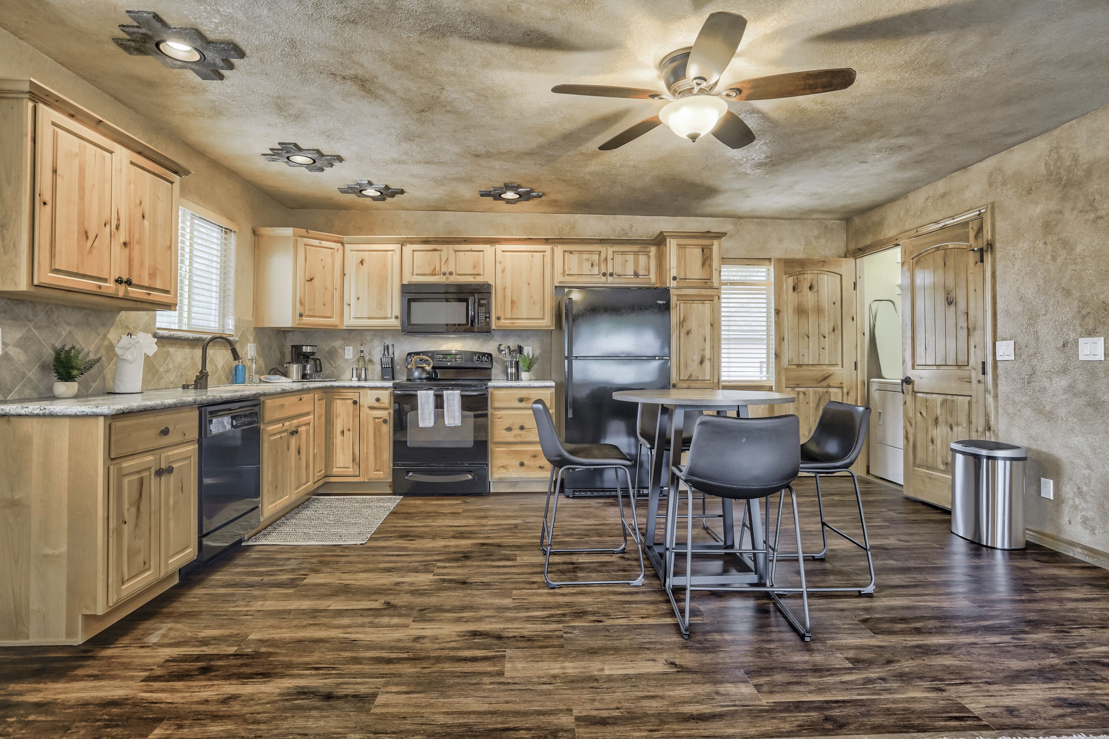 A kitchen with wooden cabinets, a microwave, a refrigerator, and a ceiling fan.