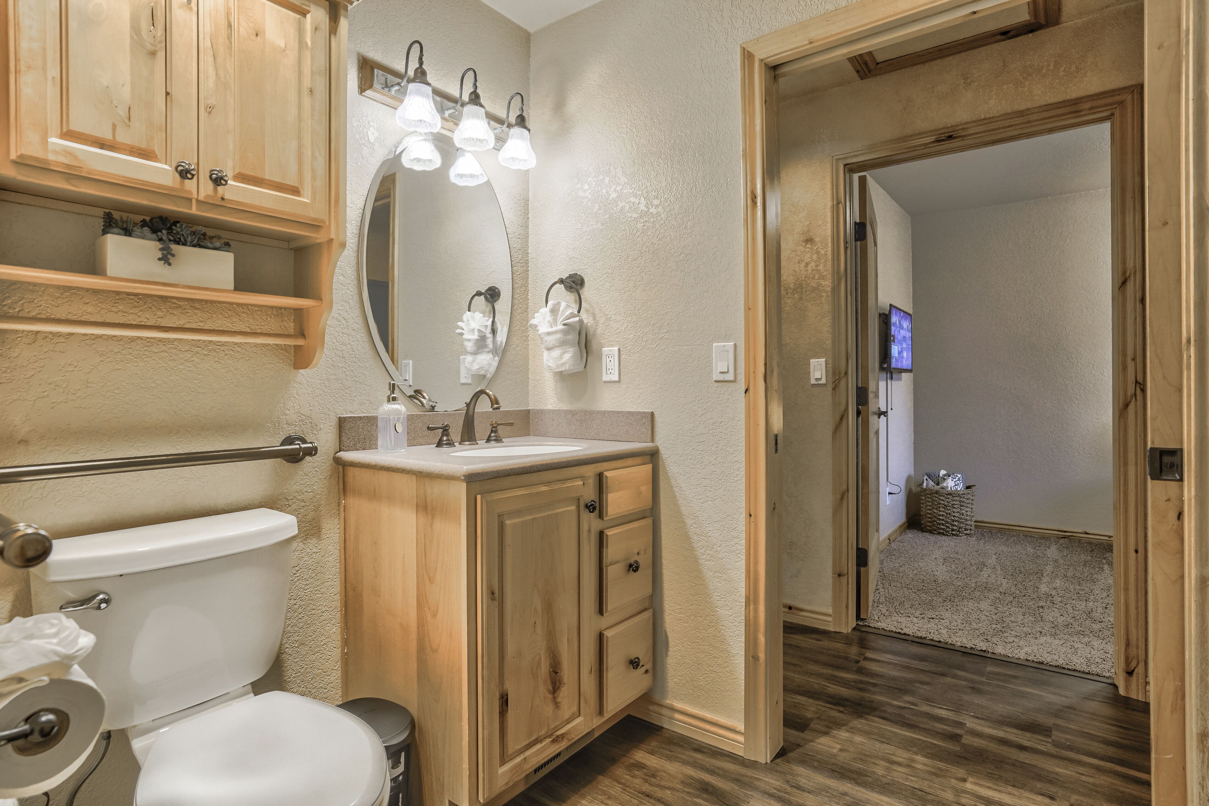 A bathroom with wooden cabinets, a white sink, and a large mirror.