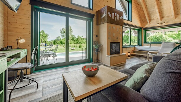 A modern interior with a dining area, a fireplace, and large windows offering a view of the outdoors.