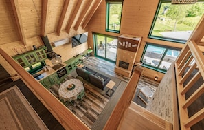 A spacious loft-style room with a high ceiling, a dining area with a round table and chairs, a sofa, and a fireplace. - Stunning home in Gospic (Gospic)
