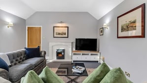 Ein Wohnzimmer mit Kamin, Fernseher und einer Couch.