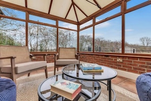 Relax in this serene sunroom with a comfortable seating area and stunning views of the surrounding landscape.