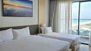 A hotel room with two beds, a large window with a view of the beach, and a painting on the wall. - Condotel Cam Ranh Beach Resort (Bac Cam Ranh)