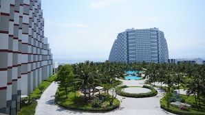 A modern hotel with a pool area, palm trees, and a view of the ocean. - Condotel Cam Ranh Beach Resort (Bac Cam Ranh)