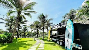 A food truck named "Ice Cube" parked on a grassy path with palm trees. - Condotel Cam Ranh Beach Resort (Bac Cam Ranh)