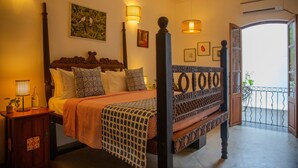 Quarto com cama, luminárias de cabeceira, ventoinha no teto e varanda com guarda-corpo.