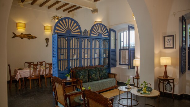 Uma sala de estar aconchegante com sofá, cadeiras de madeira, uma mesa de jantar e um painel azul decorativo.