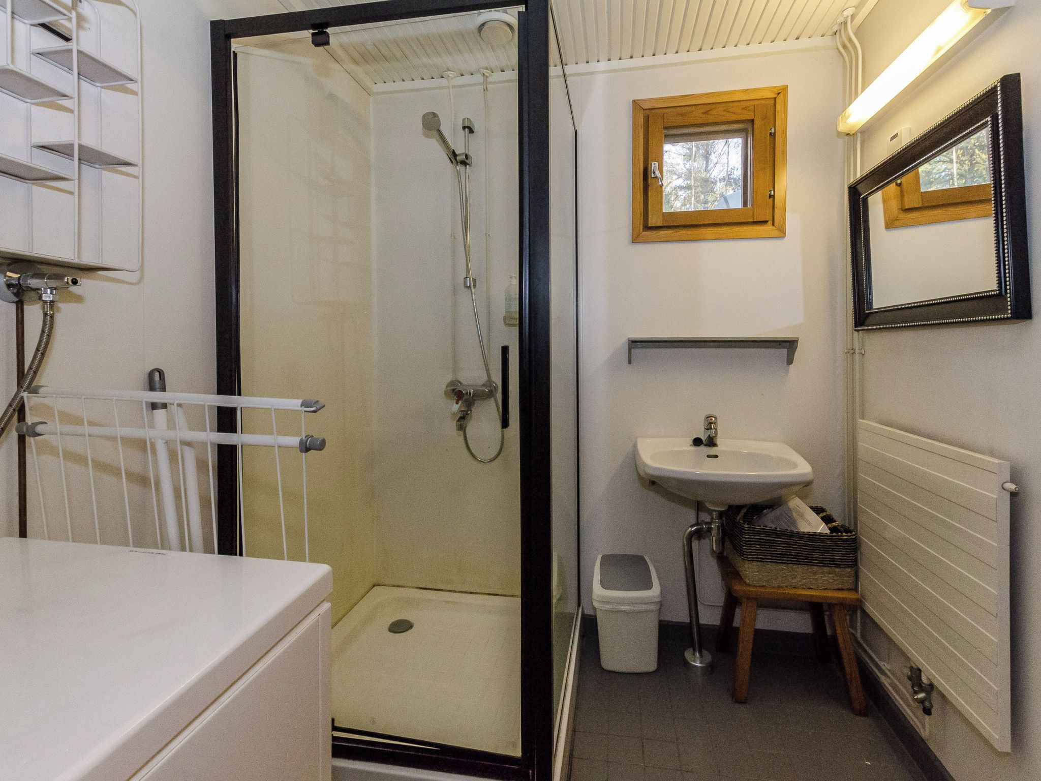 Un baño pequeño con ducha, lavamanos y una ventana.
