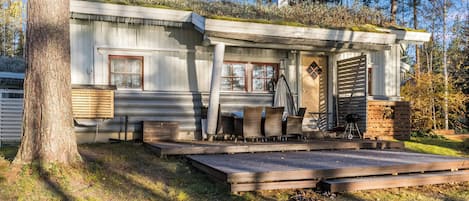 Eine Hütte mit Veranda, Sitzgelegenheiten im Freien und Grillplatz.
