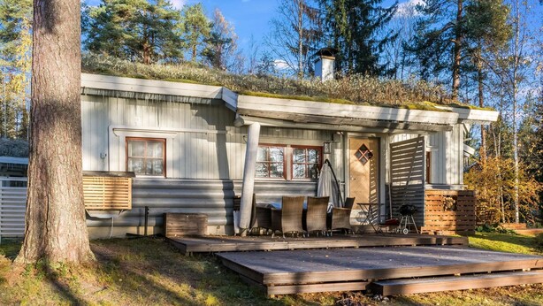 Eine rustikale Holzhütte mit Veranda, Sitzgelegenheiten im Freien und einem Schornstein.