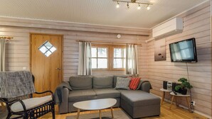 Ein gemütliches Wohnzimmer mit einer Couch, einem Couchtisch, einem Fernseher und einem kleinen Beistelltisch mit einer Pflanze.