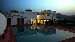 A modern house with a swimming pool, a small garden, and a well-lit exterior. - The Vanashva (Rajgarh)