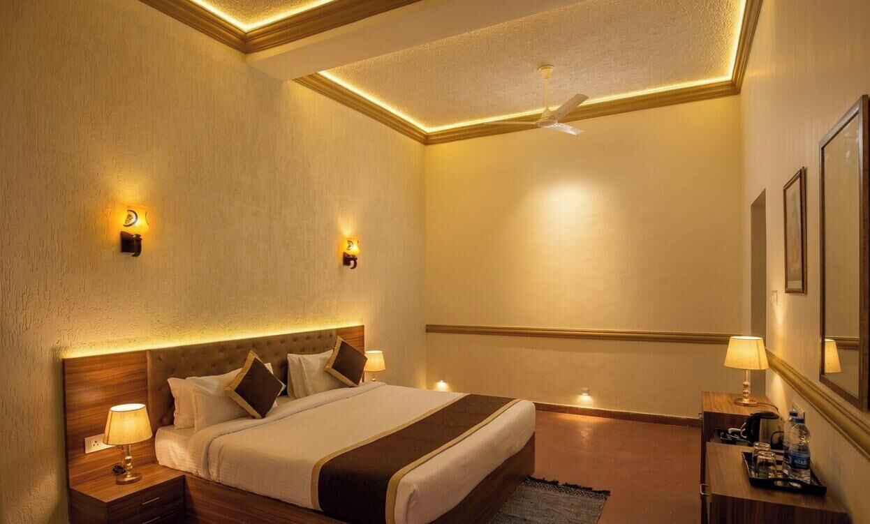 A hotel room with a bed, nightstands, wall sconces, a ceiling fan, and framed artwork.