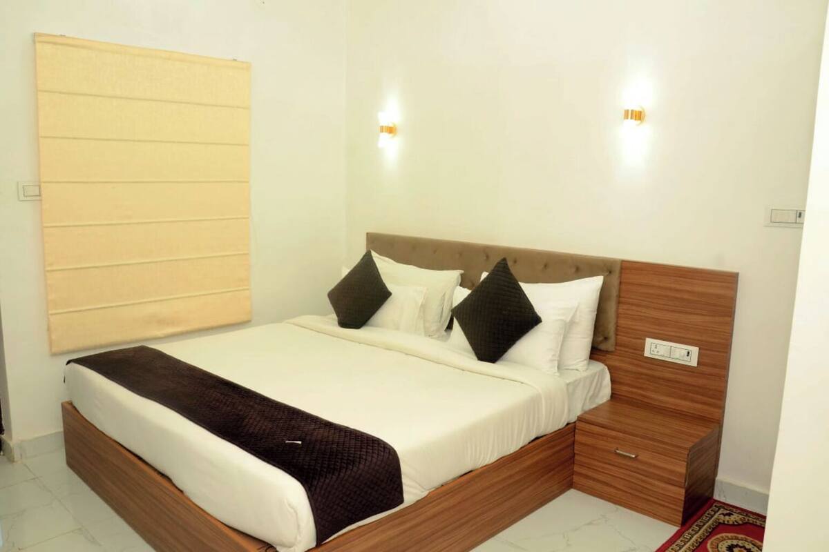 A neatly made bed with a wooden headboard, white bedding, and two black pillows.