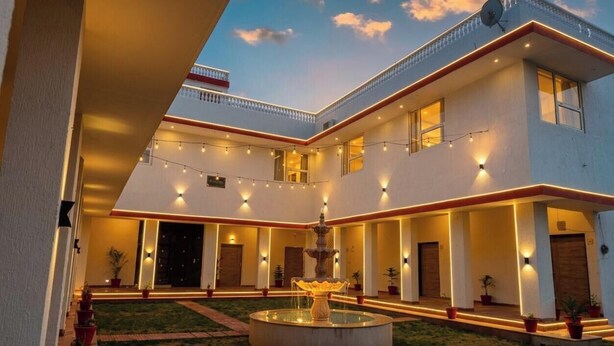 A two-story building with a courtyard, outdoor lighting, and a central fountain. - The Vanashva (Rajgarh)