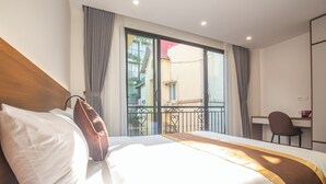 Ein Hotelzimmer mit einem großen Bett, einem Schreibtisch und Blick auf den Balkon.