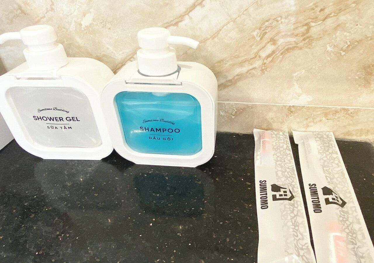 Two bottles of shower gel and shampoo on a black countertop.