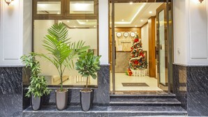 Ein Hotel Eingang mit einem Weihnachtsbaum, Topfpflanzen und einer Rezeption.