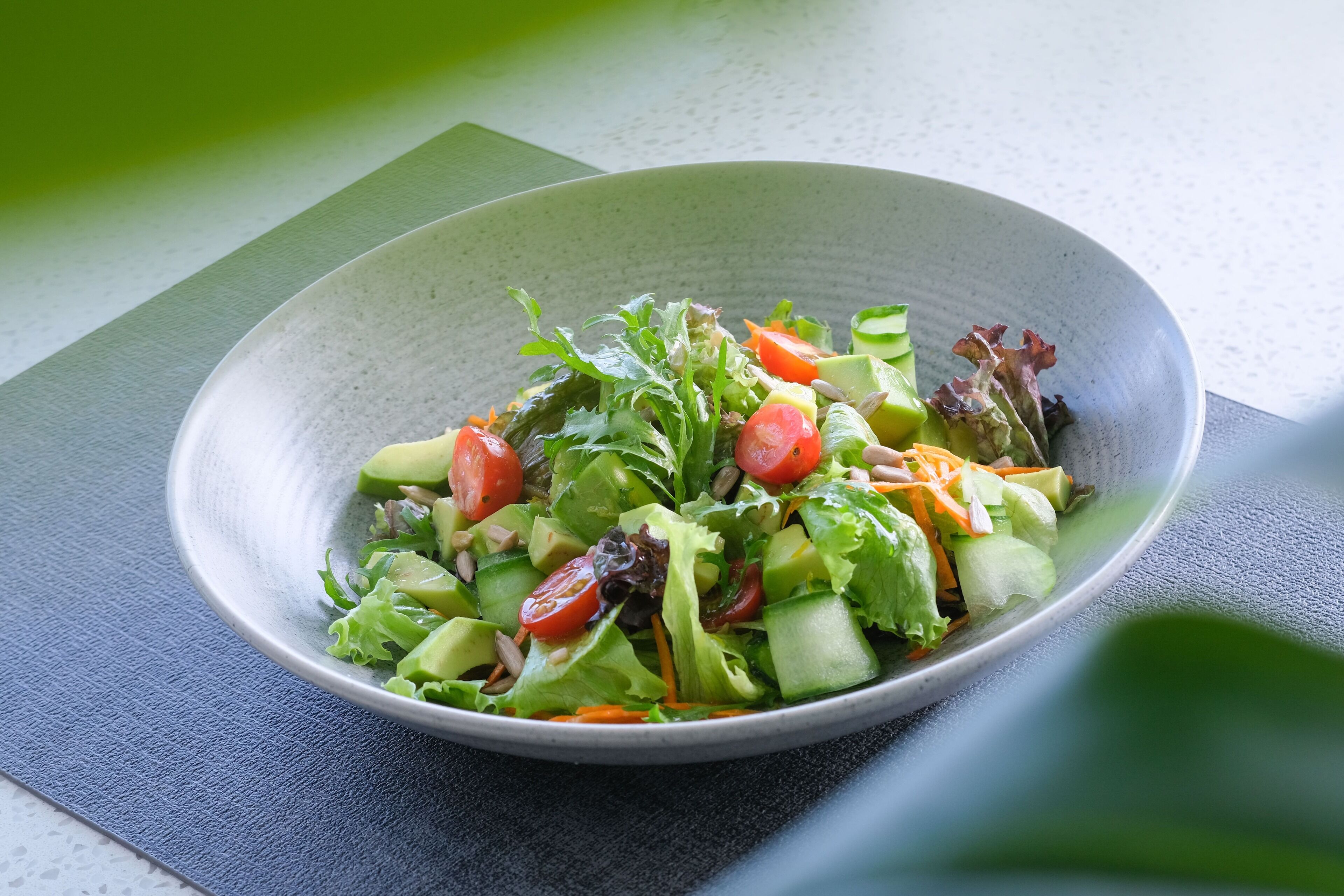 A bowl of salad on a textured mat.